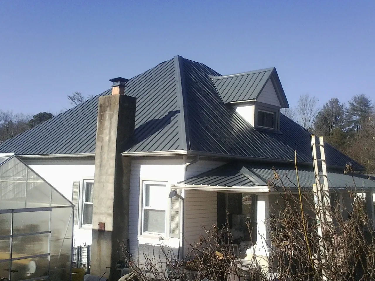 Dark blue standing seam metal roof on a white farmhouse with dormer — Slate & Tile Roof Repair by Roofing Brothers in Kearsarge