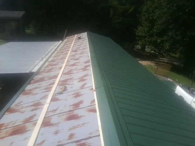 Old rusted panels beside newly installed green metal roofing — Wind Damage Roof Repair by Roofing Brothers in Kearsarge