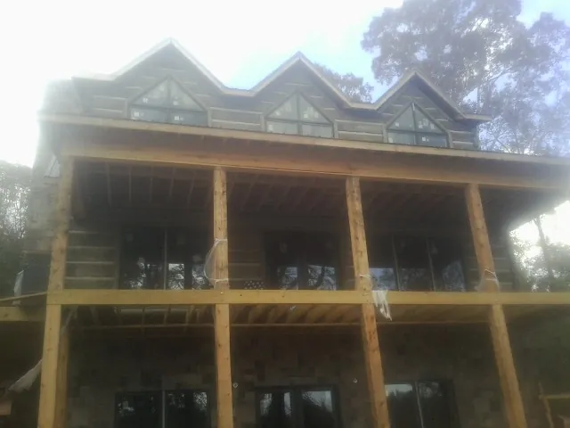 Dormers and porch framing on a large log home under construction — Roof Coating work by our crew in Kearsarge