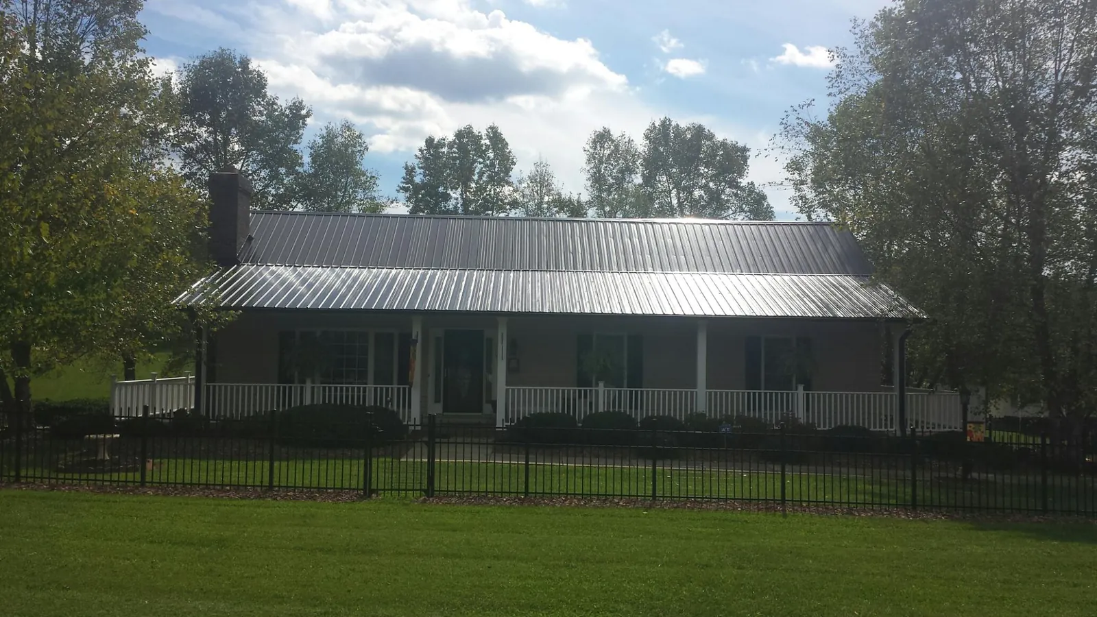 Gray metal roof on a brick ranch with a full width front porch — Gutter Guard Installation work by our crew in Kearsarge