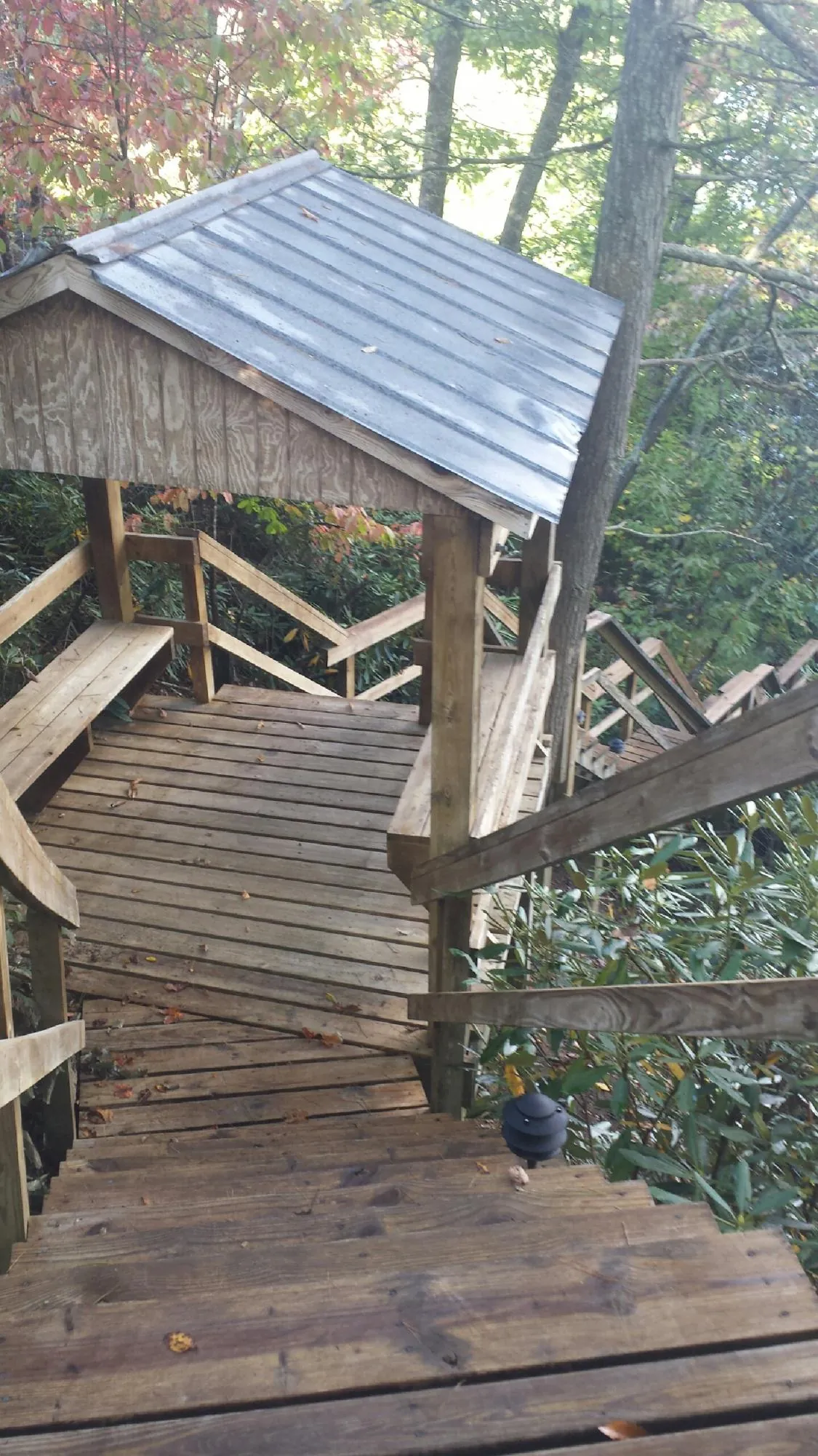 Metal roofed shelter over wooden steps on a wooded walkway — Skylight Repair & Installation work by our crew in Kearsarge