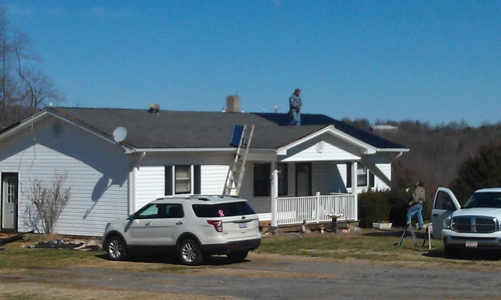 Roofers stripping shingles from a white ranch house roof in Kearsarge
