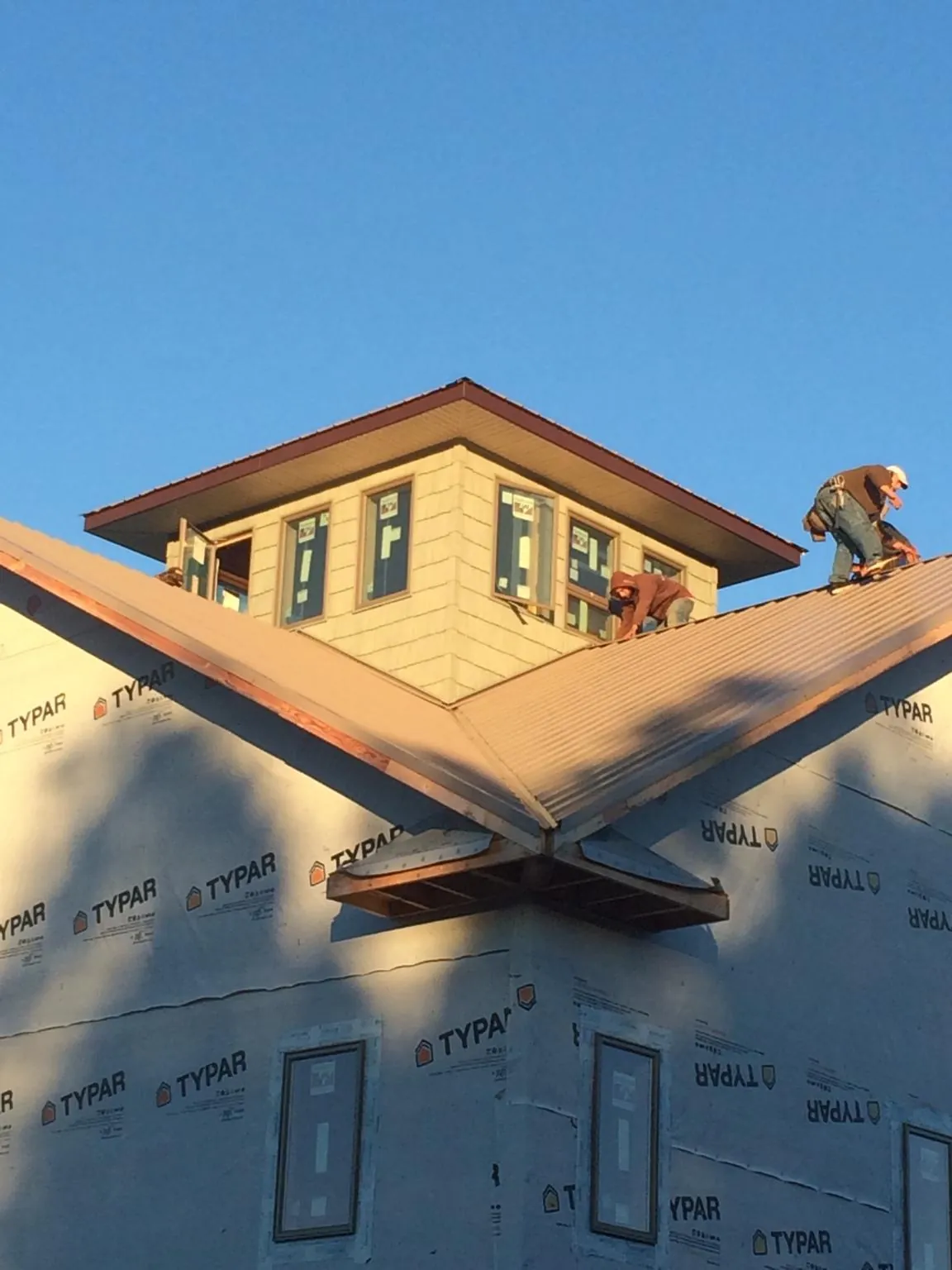 Roofers working around a rooftop cupola on a new metal roof at sunset — Roof Waterproofing in Kearsarge by Roofing Brothers